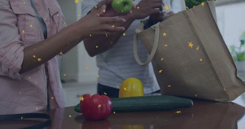 Couple unpacking groceries at kitchen counter with reusable jute tote and fresh produce