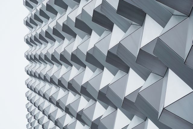 Modern building facade featuring repeating geometric patterns. Ideal for architectural magazines, design blogs, and urban development presentations, offering eye-catching visuals of innovative, contemporary structures harmonizing with urban environments for a striking visual impact.