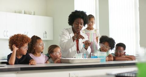 Stem classroom: female teacher leading hands-on chemistry experiment with curious students