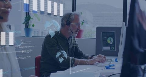 Mature man wearing headset working at modern office desk with holographic data overlays