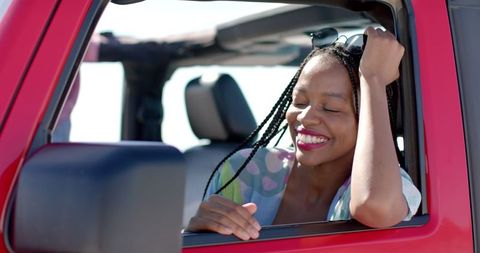Smiling woman enjoying freedom on road trip in convertible car