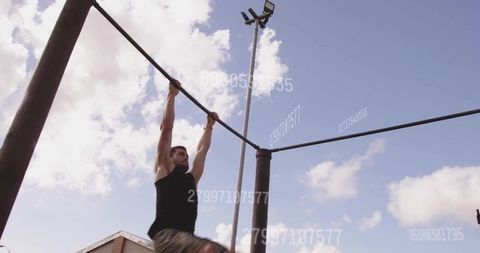 Athlete practicing pull ups against clear blue sky