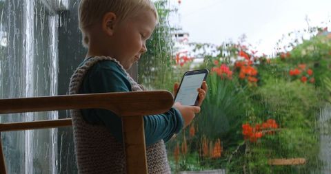 Caucasian child engaged in mobile game during rainy day