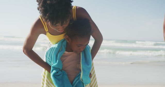 African american mother drying her daughter with a towel at the beach. family travel and vacation concept