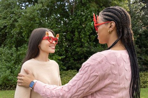 Asian and african american friends wearing festive reindeer glasses smiling in sweaters