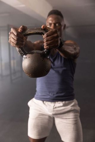 Athlete holding kettlebell for strength training and functional fitness in modern gym