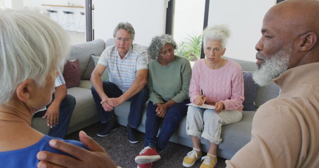 Diverse group of senior friends gathering in a living room for a meaningful conversation. This image can be used for promoting elderly community activities, support groups, social interactions among seniors, or showcasing positive social engagements for the elderly.