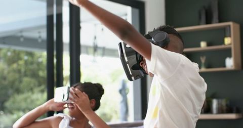 Siblings Enjoying Virtual Reality Technology Together at Home