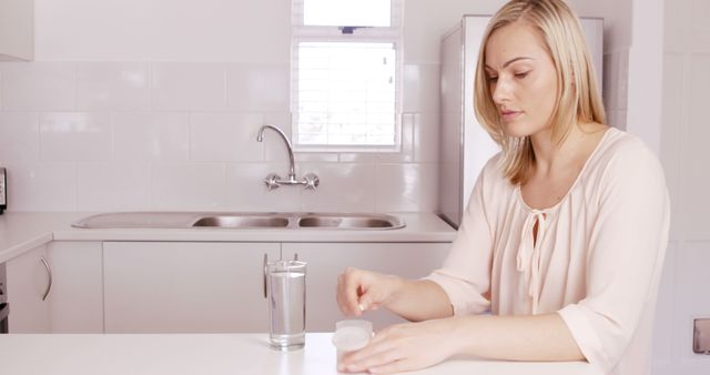 Woman taking pills in the kitchen - Download Free Stock Photos Pikwizard.com