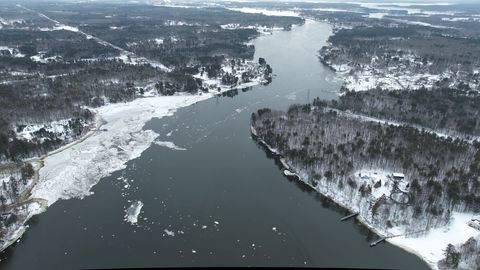 Aerial winter river winding through snow-covered islands and icy shoreline landscape