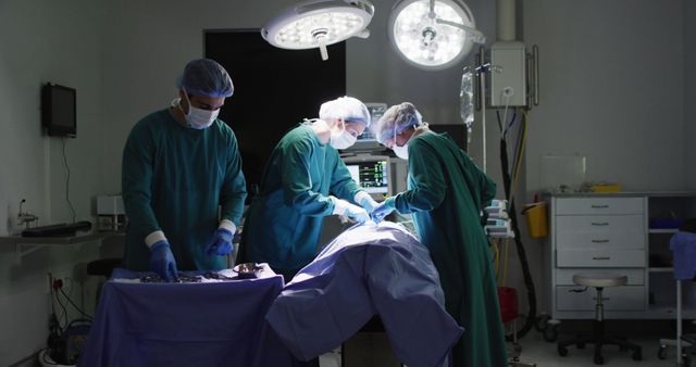 Surgical team performing a medical procedure in an operating room. Three surgeons in green scrubs and masks working under bright surgical lights. Medical equipment is visible in the background. Use for topics related to healthcare, surgery, medical profession, and hospital scenes.