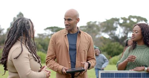 Community workshop demonstrating portable solar panel setup with diverse group outdoors