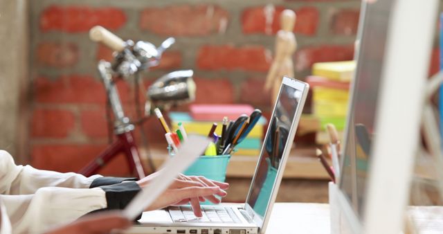 Person Working on Laptop in Modern Office with Red Brick Wall - Download Free Stock Images Pikwizard.com