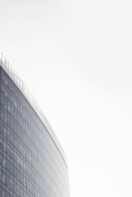 This depiction of a modern glass office building with a clear, bright sky lends itself perfectly to corporate design projects, business presentations, websites, and promotional materials that require a sleek, urban look. Highlighting clean lines and contemporary architectural elements, this image is suitable for content related to commercial real estate, urban development, business growth, and modern lifestyle themes.