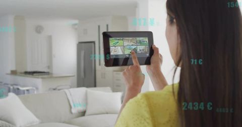 Korean woman controlling smart home security from tablet in modern open-plan living room
