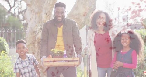 Happy family gardening together smiling by tree in sunny day