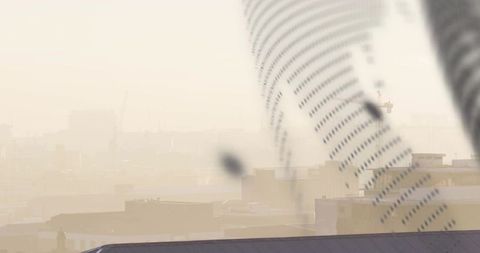 Perforated vent duct cutting diagonal over hazy industrial rooftops and urban smog