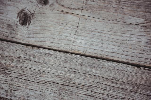 This image features a close-up view of weathered wooden planks, showcasing the natural grain and texture of aged wood. Ideal for use as a background in design projects, websites, or presentations that require a rustic or vintage feel. It can also be used in woodworking, construction, or home decor contexts to illustrate materials and textures.