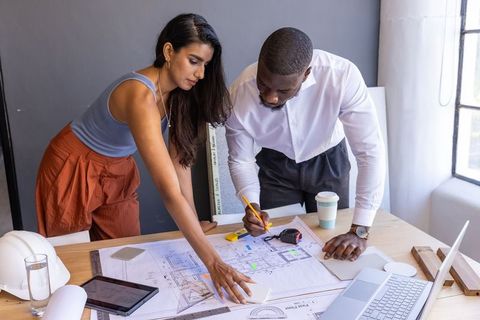 ArchiTeam Collaborating on Blueprint Strategy in Modern Office