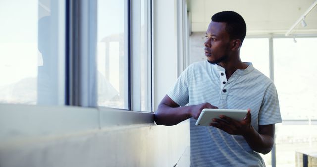 Man Holding Tablet Looking Out Window in Modern Office - Download Free Stock Images Pikwizard.com