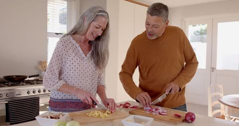 Senior Couple Joyfully Preparing Vegetables Together in Modern Kitchen