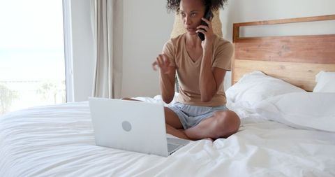 Woman on Bed Multitasking with Laptop and Smartphone