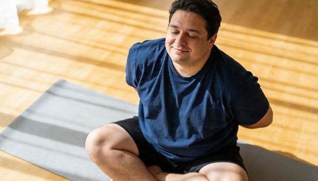 Sunlit meditation man sitting cross-legged on mat practicing mindful breathing at peace