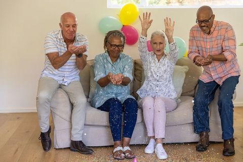 Joyful Senior Friends Tossing Confetti in Living Room Celebration