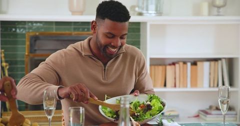 Friends sharing meal with large salad bowl socializing at home