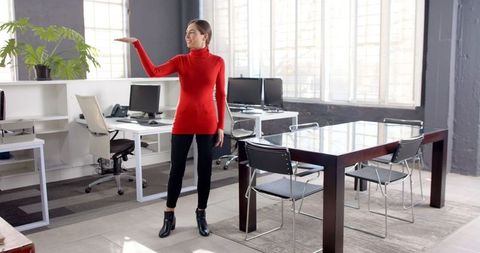 Businesswoman in red providing a pointing gesture in modern office setting