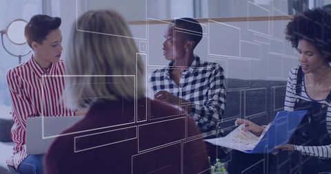 Diverse team collaborating in modern lounge discussing strategy with laptop and documents