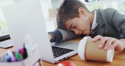 Exhausted Young Boy in Suit Sleeping at Desk with Coffee Cup - Download Free Stock Images Pikwizard.com
