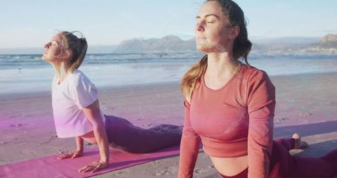 Women Practicing Yoga Poses on Scenic Sunset Beach