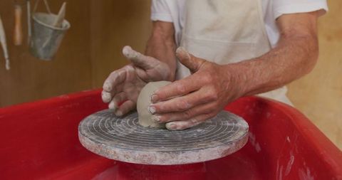 Senior artisan shaping clay on potter's wheel in studio