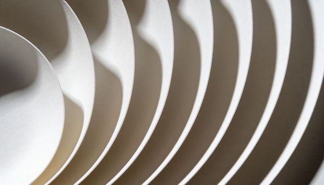 Layered curved paper arcs creating monochrome minimalist geometry and shadow patterns