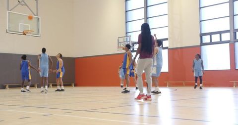 Basketball Team Practicing with Coach in Indoor Gymnasium