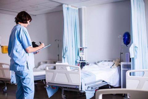 Nurse recording patient information in hospital ward