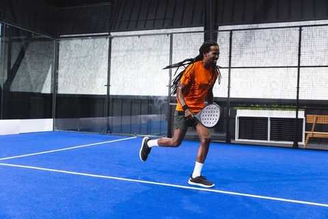 African American Man Playing Padel on Blue Court in Sports Attire