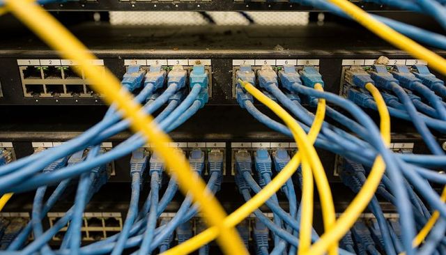 Tangled network cables connecting switches and patch panels in busy server rack