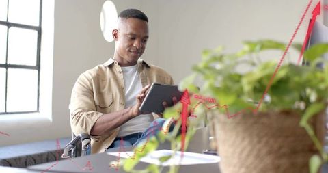 Young professional using tablet analyzing rising sales graph in bright home office