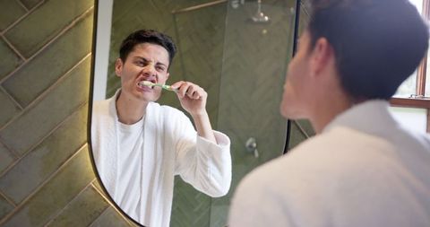 Person Brushing Teeth in Bathroom for Morning Routine