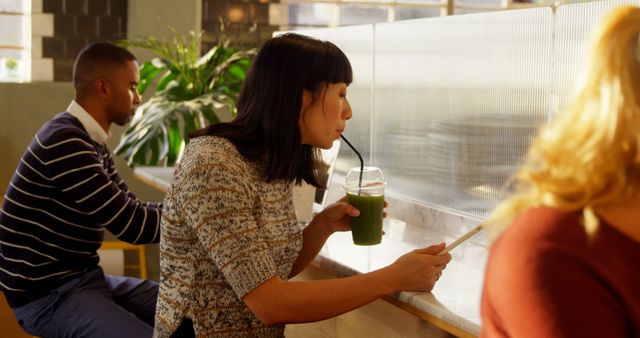 Woman Drinking Green Smoothie While Taking Notes in Cafe - Download Free Stock Images Pikwizard.com