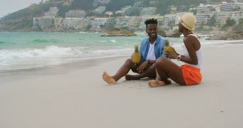 Joyful African American Couple Sharing Pineapple Drinks by Ocean