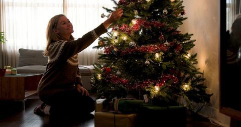 Senior Woman Decorating Christmas Tree at Home with Joy