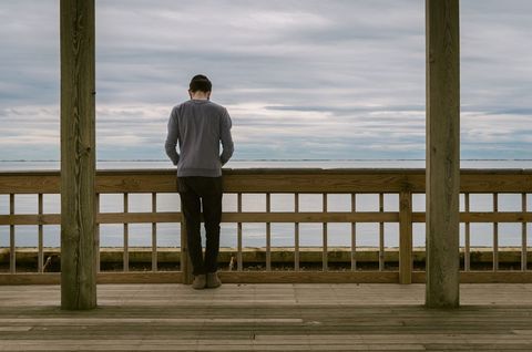 Man Contemplating by the Seaside on Wooden Deck