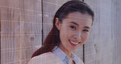 Asian Businesswoman Analyzing Financial Data with Digital Graph Overlay