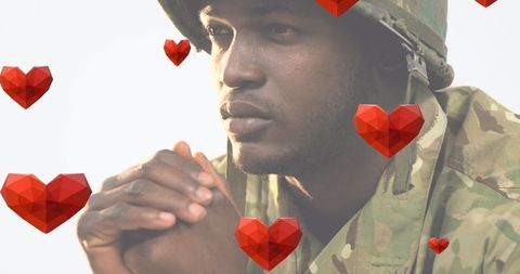 Praying soldier with falling hearts illustrating faith and patriotism