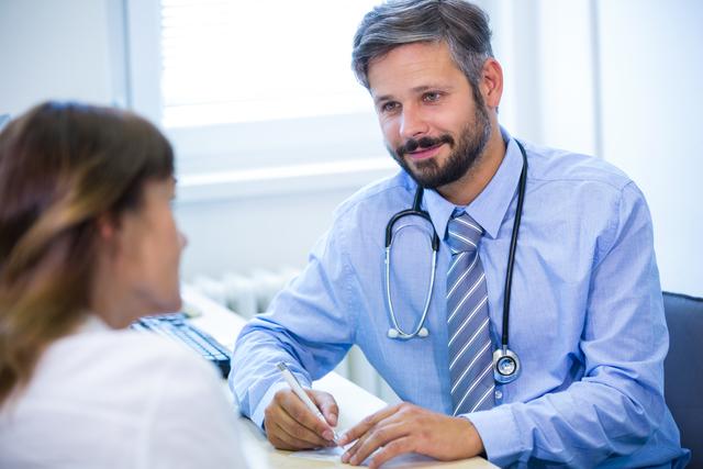 Doctor attentively listening to patient in medical office, taking notes, and offering professional advice. Ideal for use in healthcare, medical consultation, patient care, diagnosis, treatment, and hospital settings to depict professionalism and patient-doctor interactions.