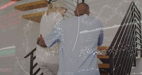 Caregiver supporting senior woman climbing stairs at home with augmented data HUD overlay