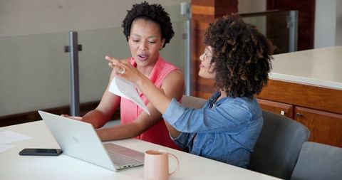 Joyful Couple Exploring Laptop Insights at Home Kitchen Table